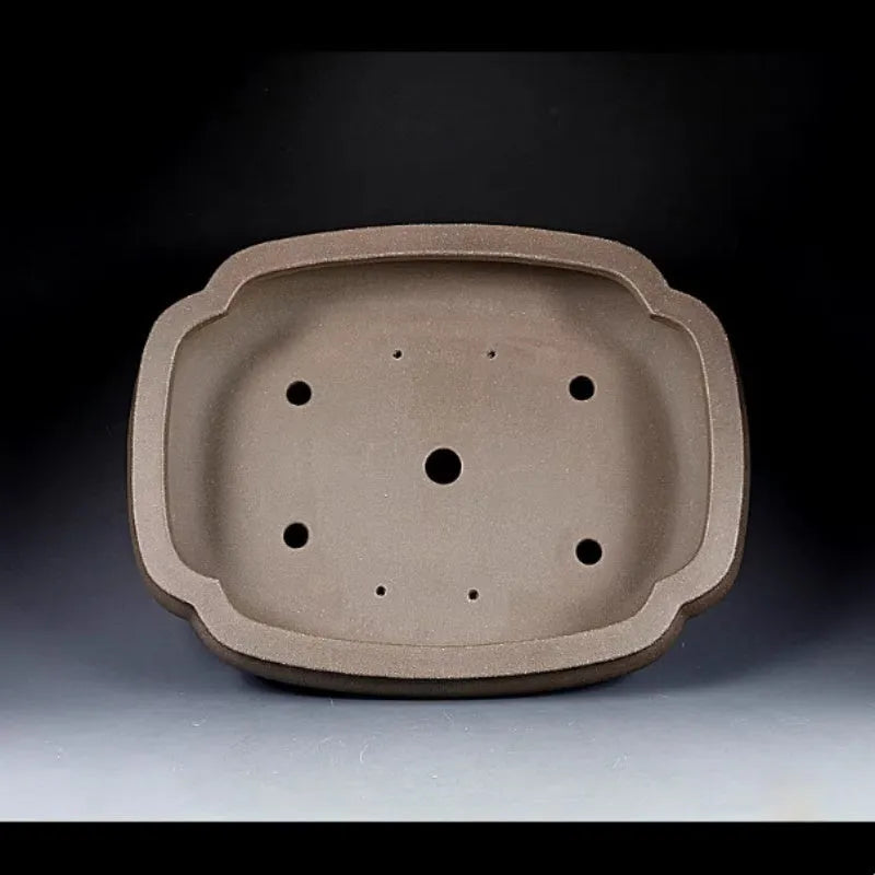 Handmade antique papaya-shaped purple clay flower pot on a tabletop.