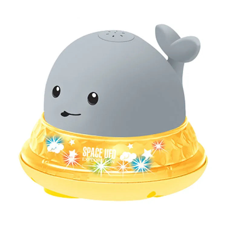 Automatic electric whale bath toy spraying water with LED lights on, floating in a baby bath.
