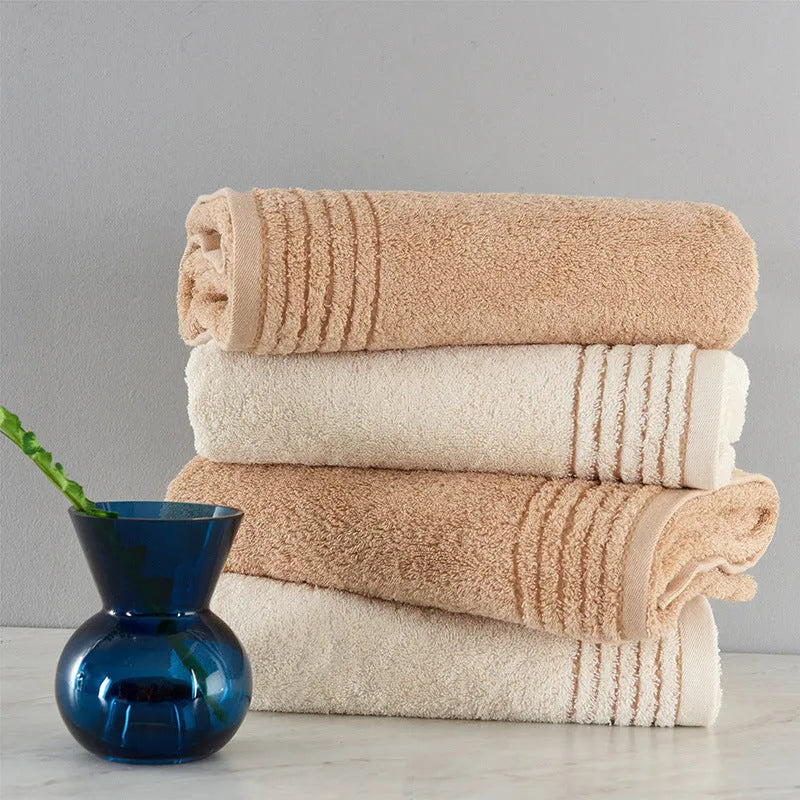 Beige and brown cotton towel set showing three sizes: square face cloth, hand towel, and bath towel.