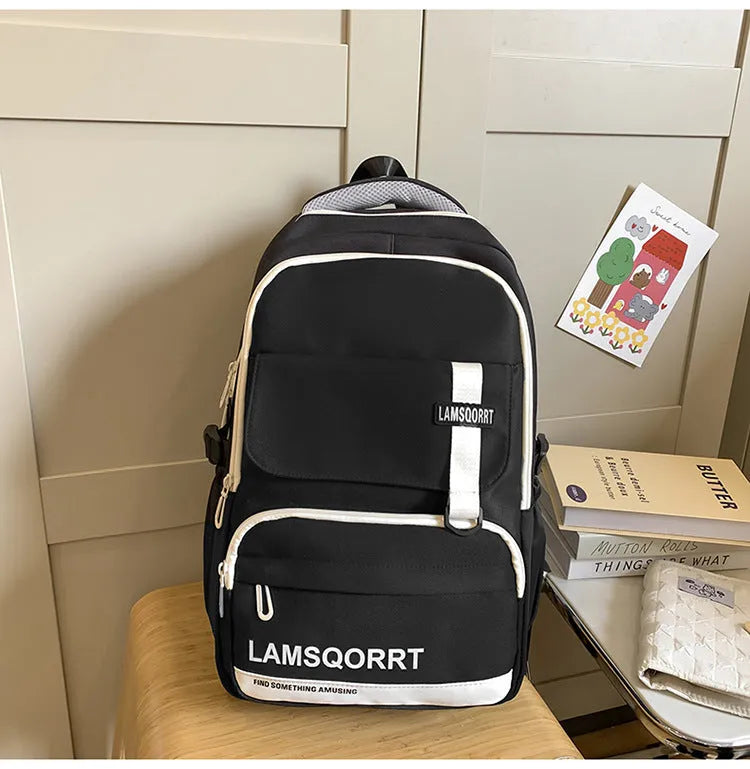 Nylon school backpack in green with pendant, showing curved shoulder straps and sewing line detail.