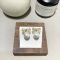 Silver tone micro inlaid zircon bow pearl stud earrings with cubic zirconia and faux pearls on white background