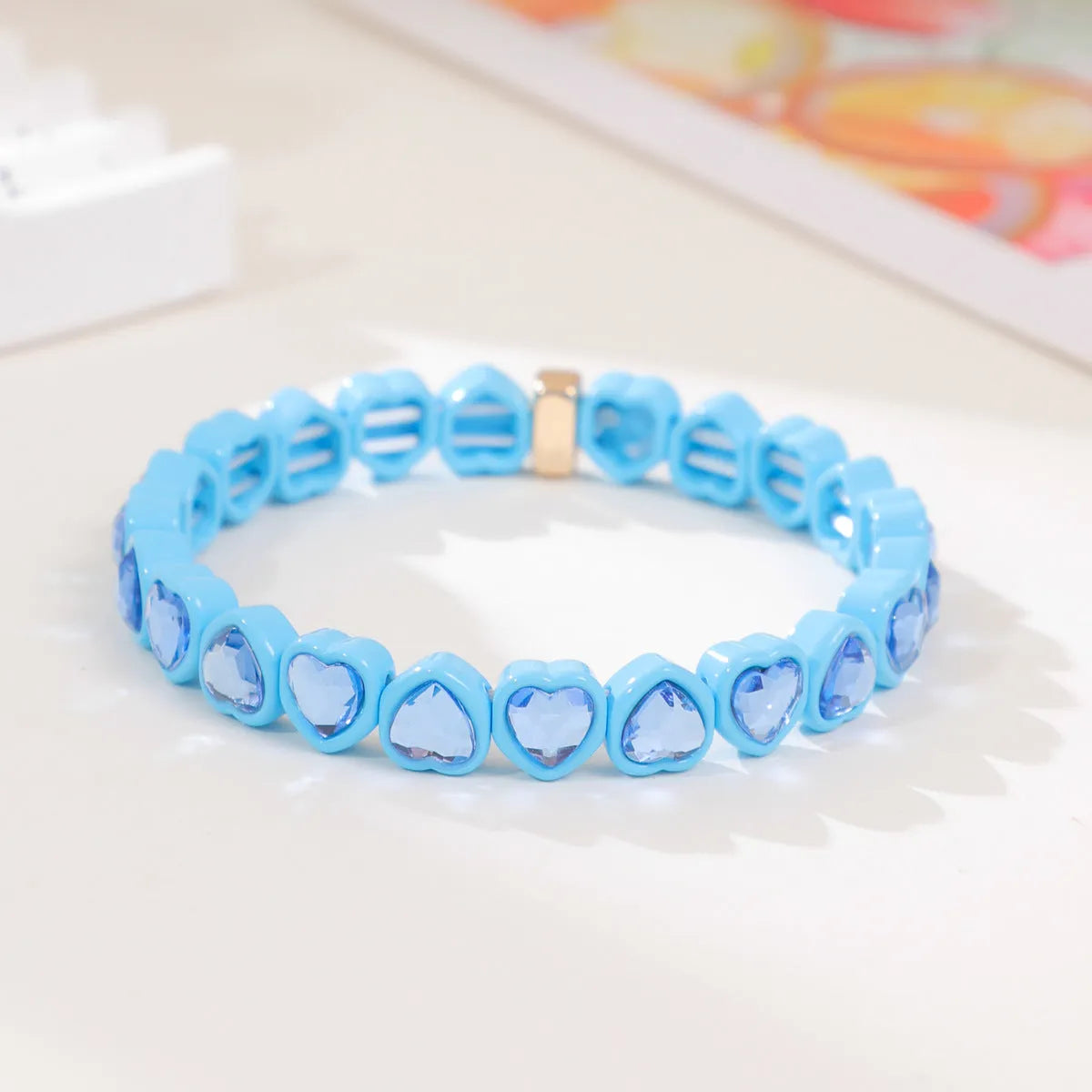 Colourful enamel finish alloy heart charm on a black stretch bracelet band.