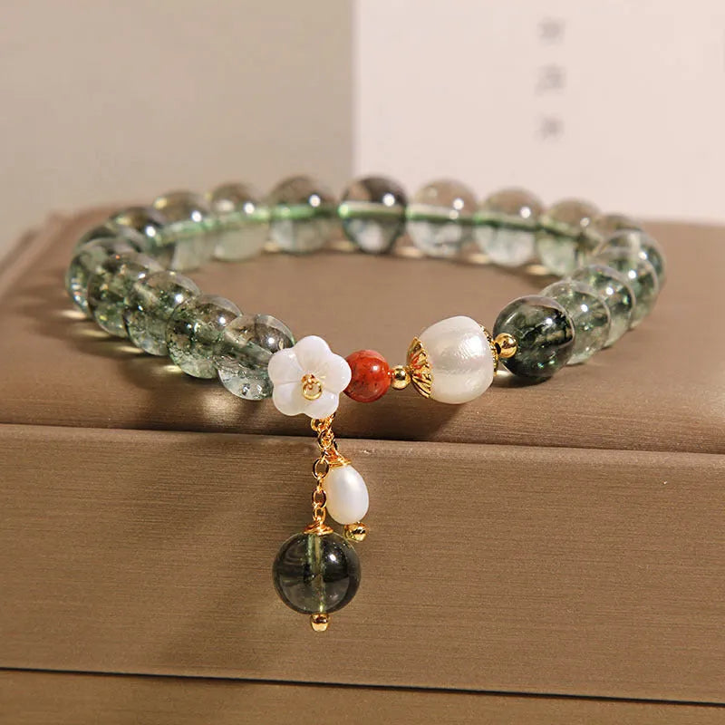 Green phantom quartz crystal bracelet with a silver shell flower charm on a model's wrist.