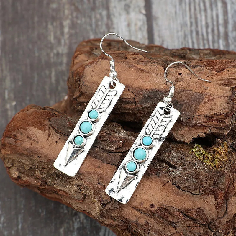 Geometric silver earrings with turquoise inlay pattern and retro styling on long strip design