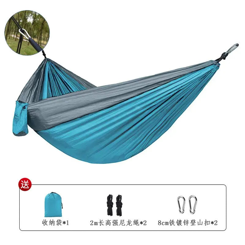 Blue parachute nylon outdoor camping hammock hung between two trees.