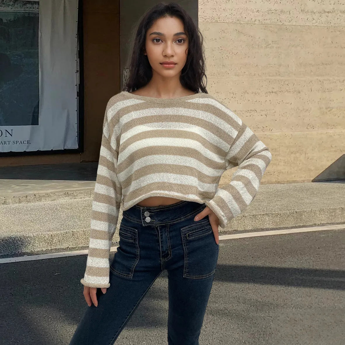 Woman wearing a striped long-sleeved sweater with an exposed navel, showcasing front and back wearable design in mercerised cotton.