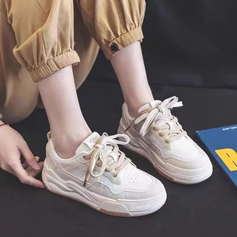 Women's beige and pink low-top lace-up sneakers with a rubber sole on a white background.
