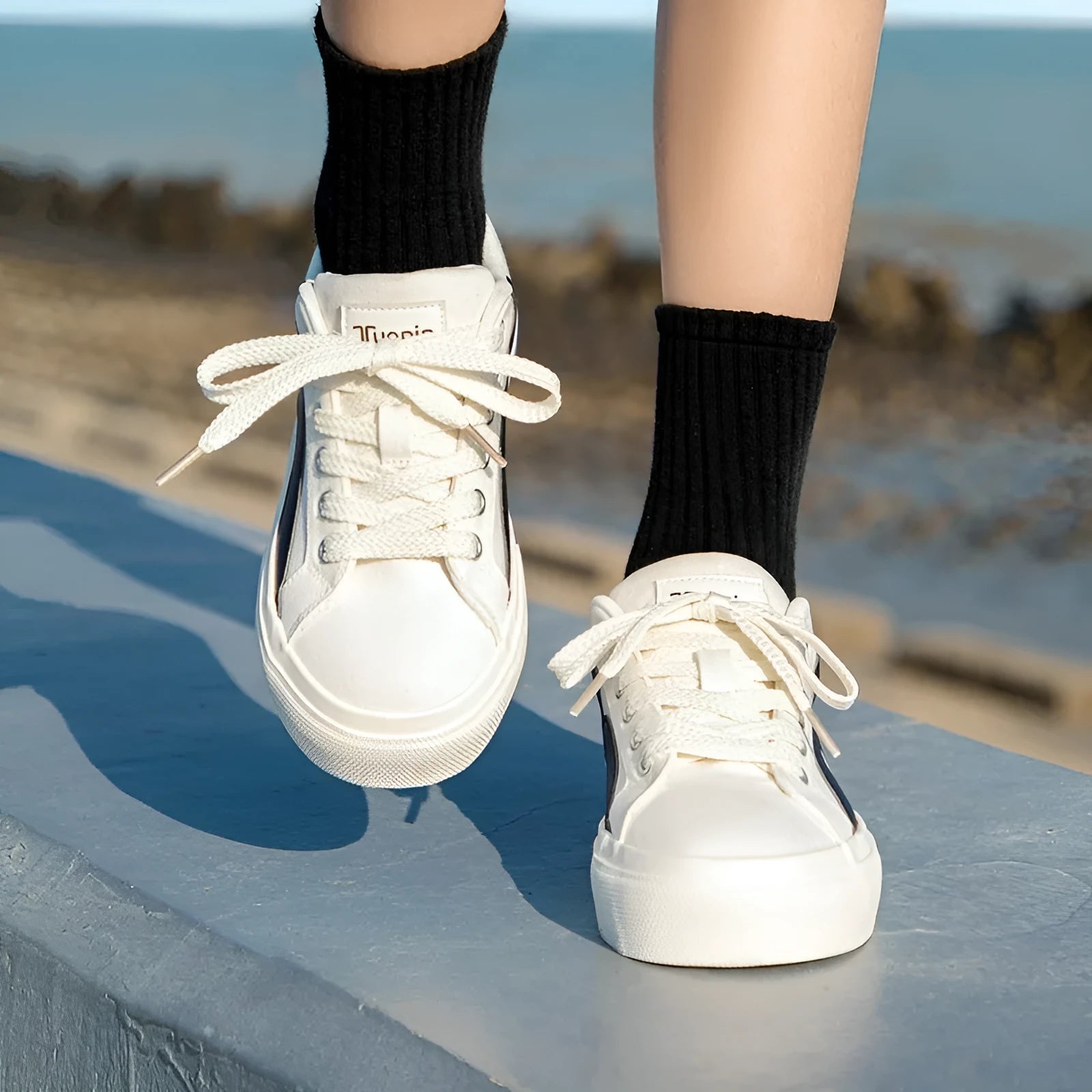 Women's low-top board shoes in a black and white colour combination, showing round toe and front lace-up design.