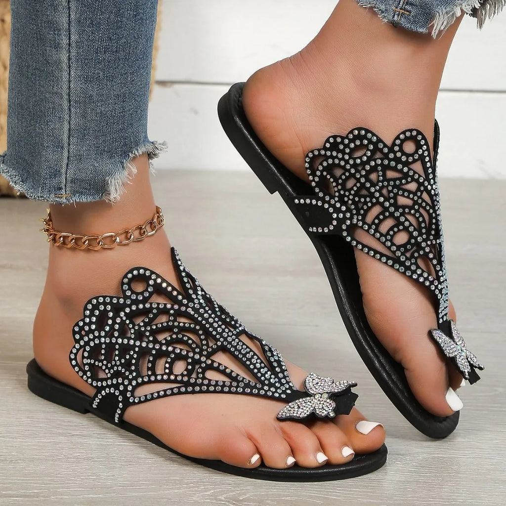 Women's black slip-on sandals with rhinestone details and flip-toe design on a white background