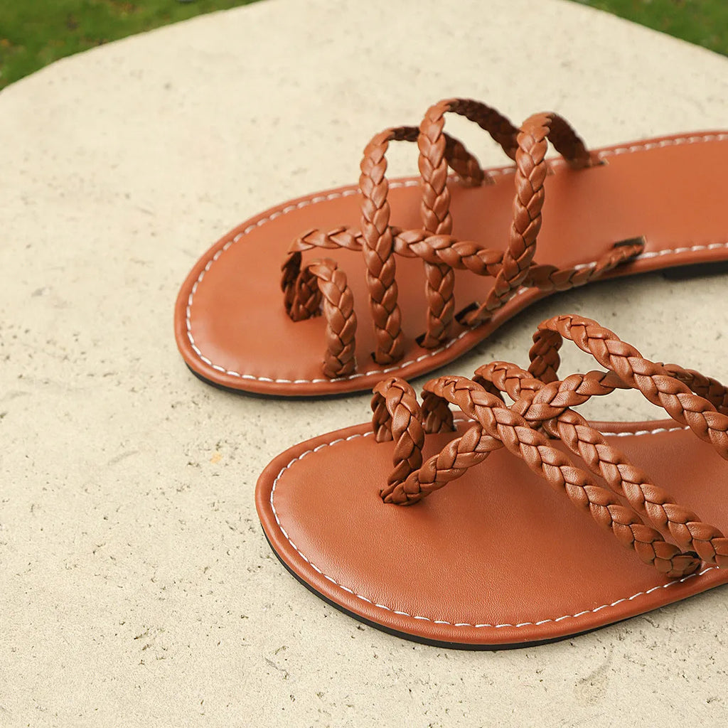 Women's black clip-toe woven flat sandals with a rubber sole on a plain background.