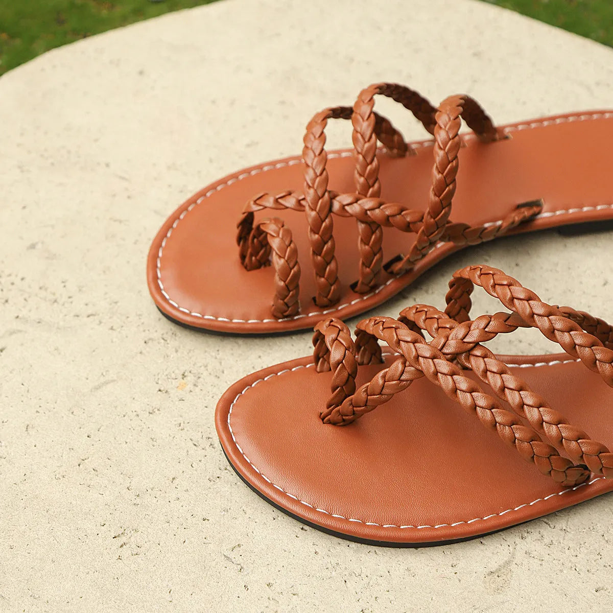 Women's black clip-toe woven flat sandals with a rubber sole on a plain background.