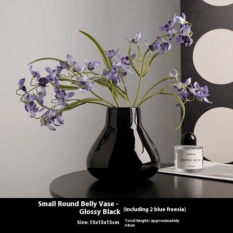 Black and white ceramic round belly french style decorative vase with two artificial flowers.