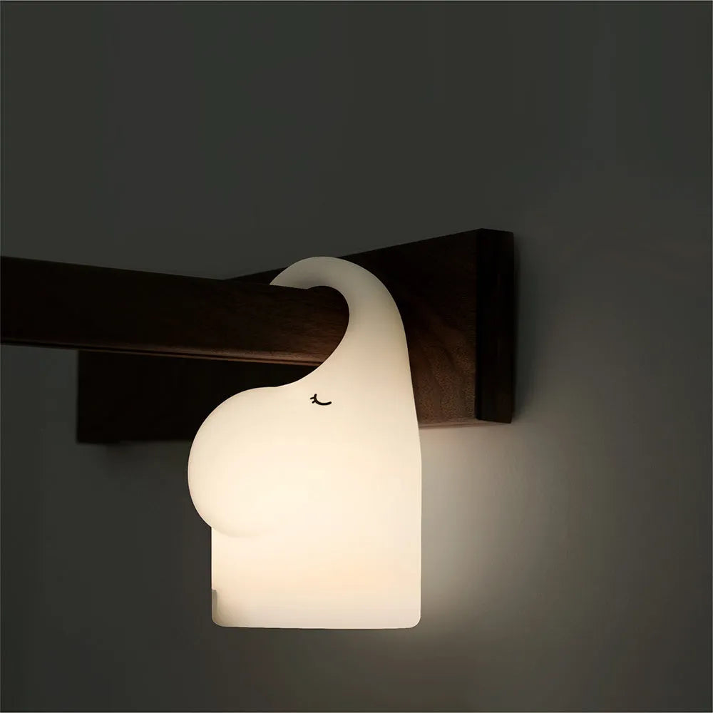DOMI Elephant-shaped silicone USB night light with warm white glow on a bedside table.