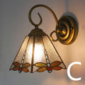 A coloured stained glass wall lamp mounted on a corridor wall, showing one of six available style variants.