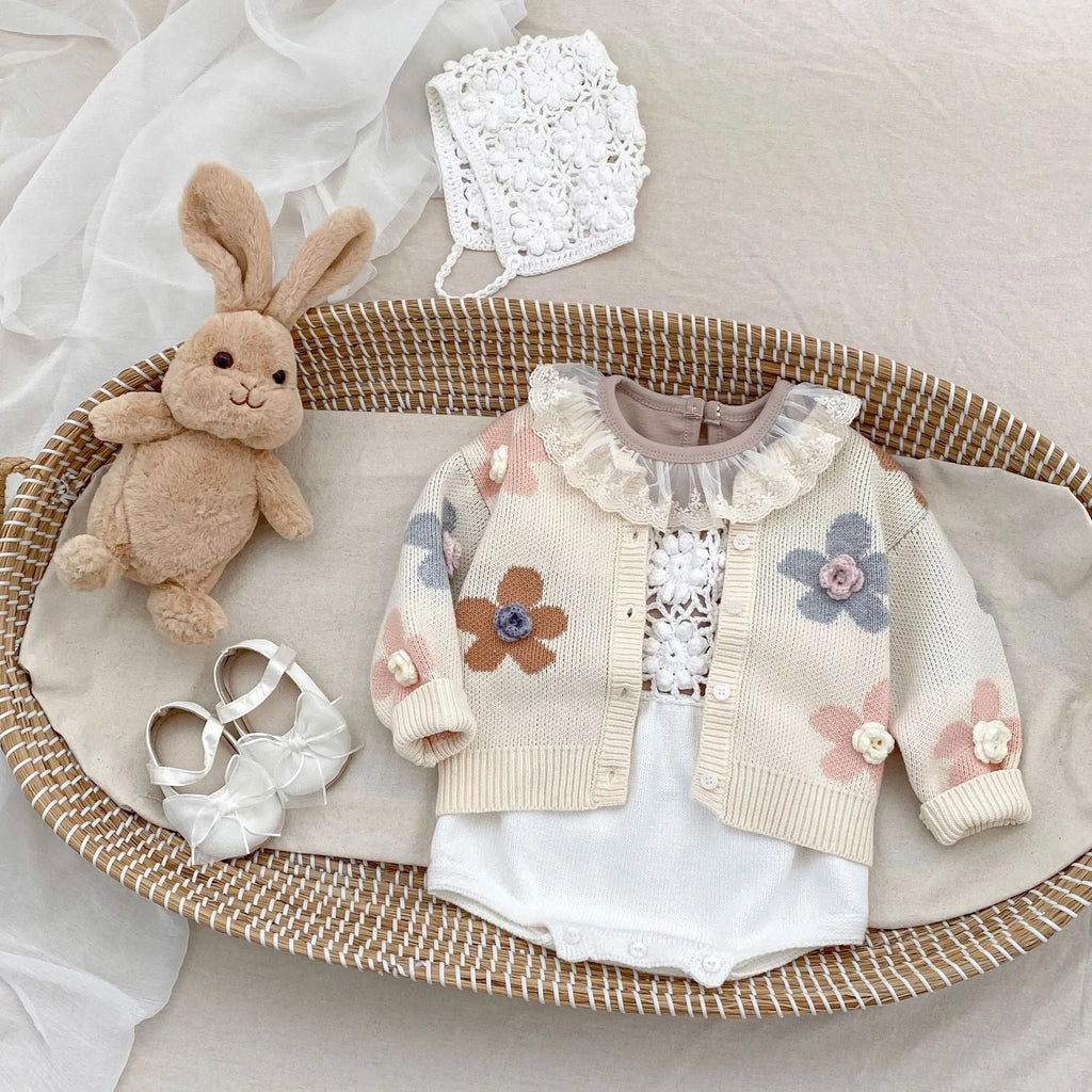 Beige baby romper with flower cutout strap and matching hat on a baby girl