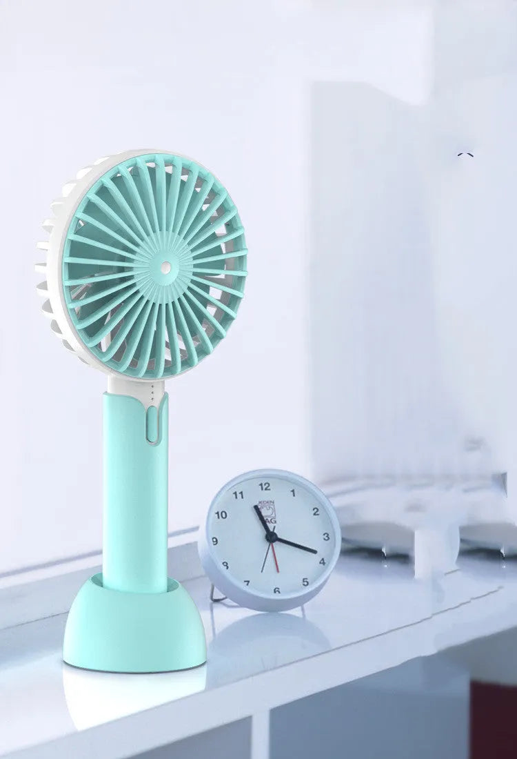 Blue handheld mini USB electric fan with oscillation feature on a desk.