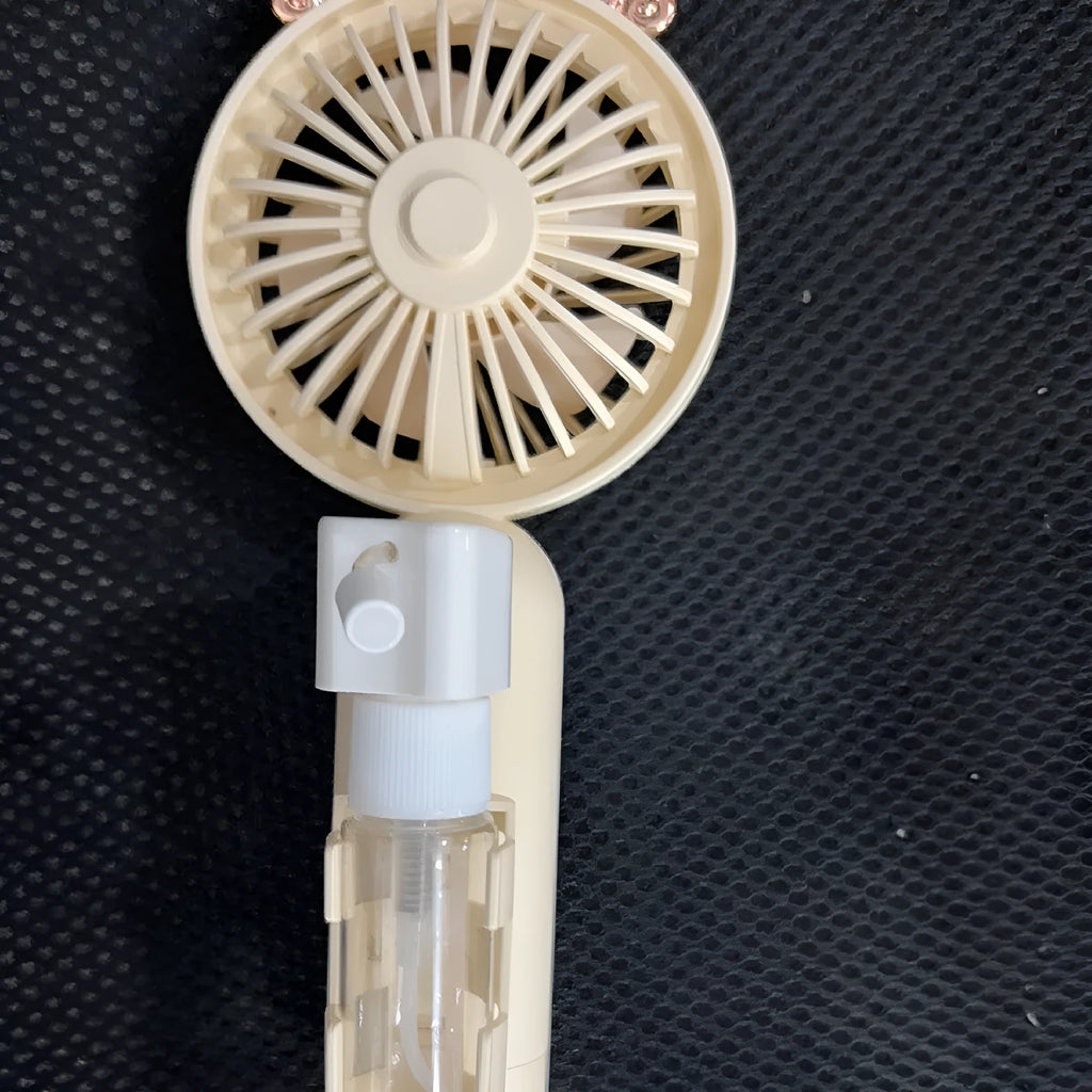 Compact apricot-coloured USB personal fan with a white plastic nozzle on a desk.