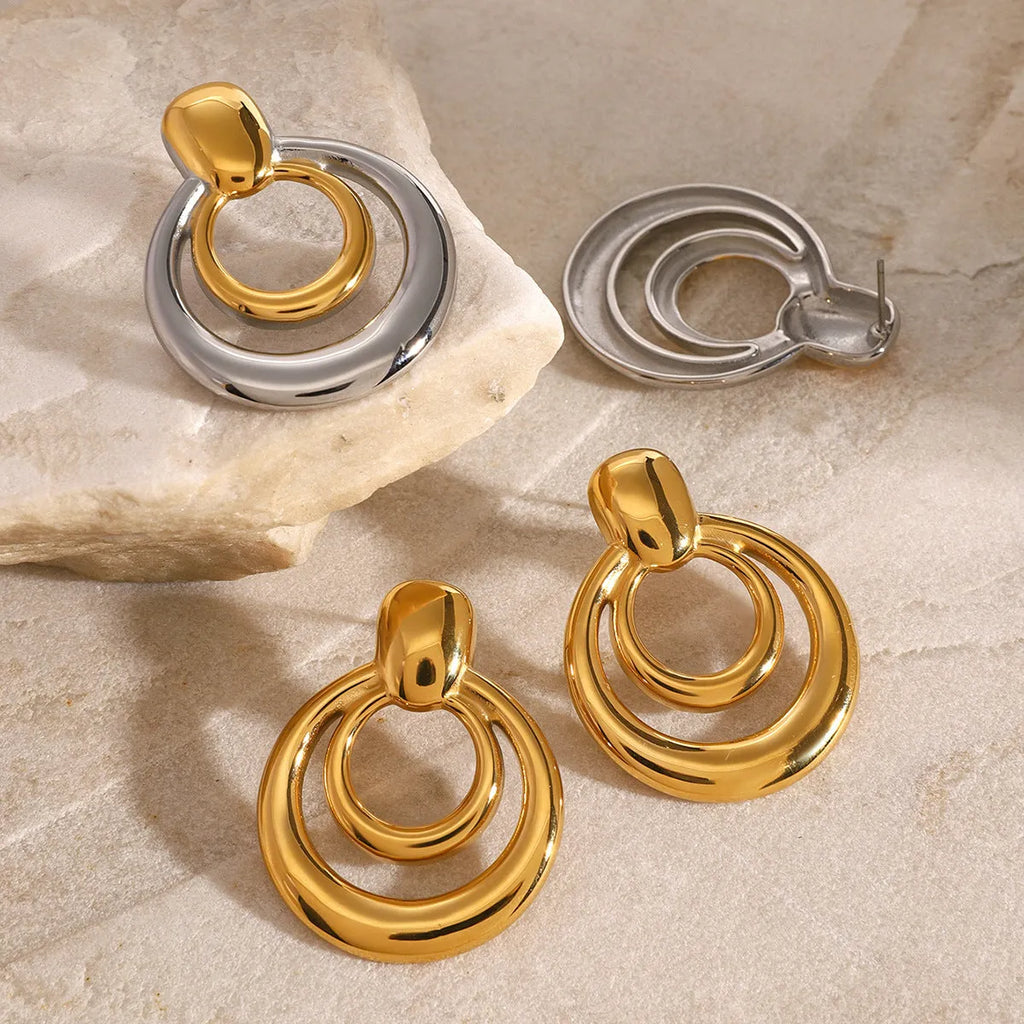 Gold-plated geometric stud earrings with hollow double-layer round design on titanium steel backing.