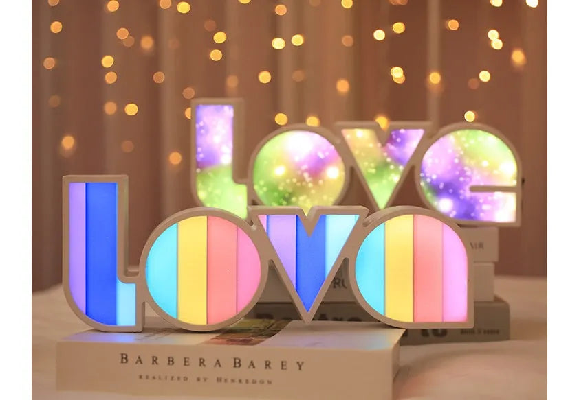 Colourful LED LOVE light decoration with rainbow lampshade on a table.