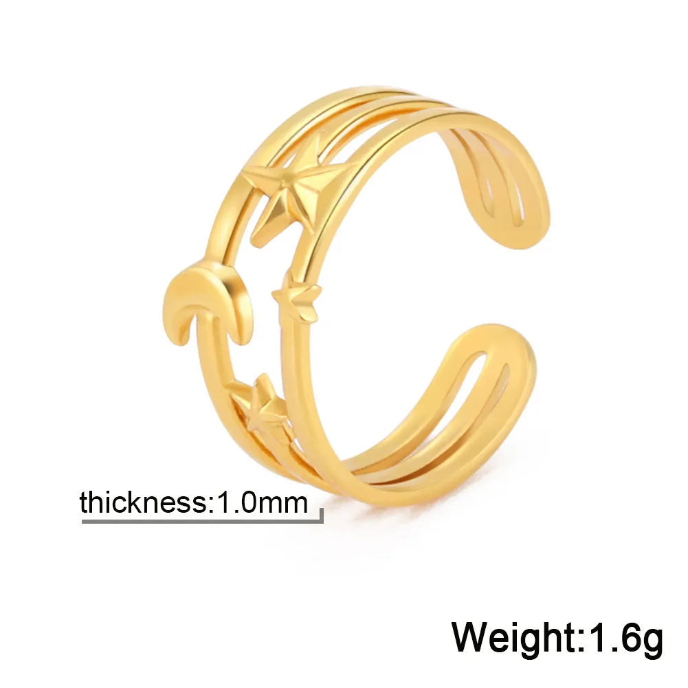 Gold electroplated stainless steel star shaped opening ring on a plain background