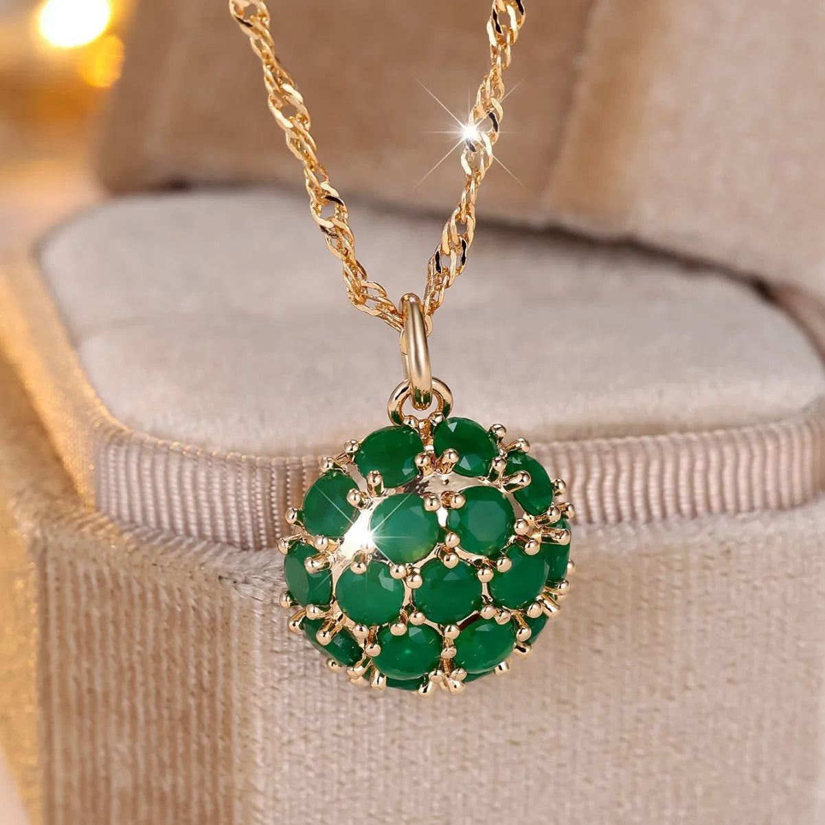Round emerald pendant necklace with diamond surround on champagne gold chain
