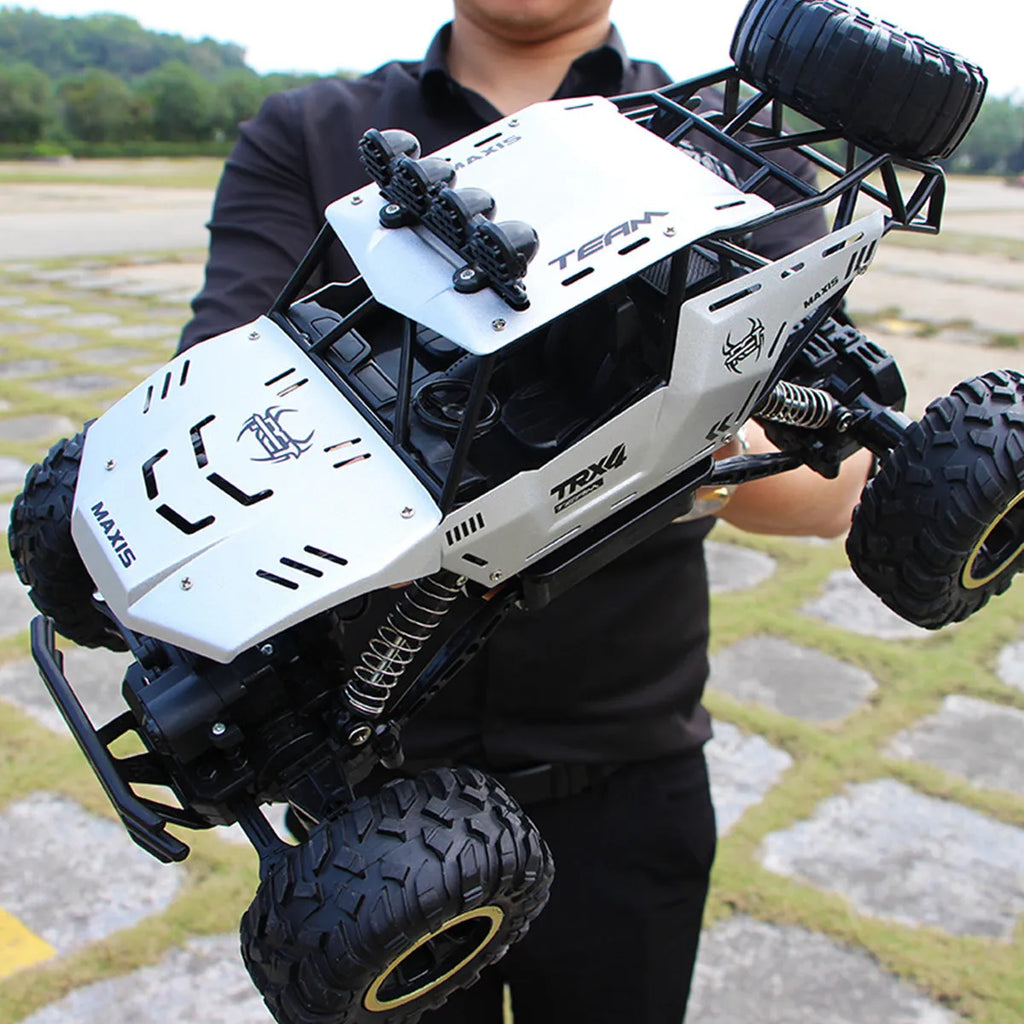 Large black 4WD remote control off-road climbing car on a rocky surface.