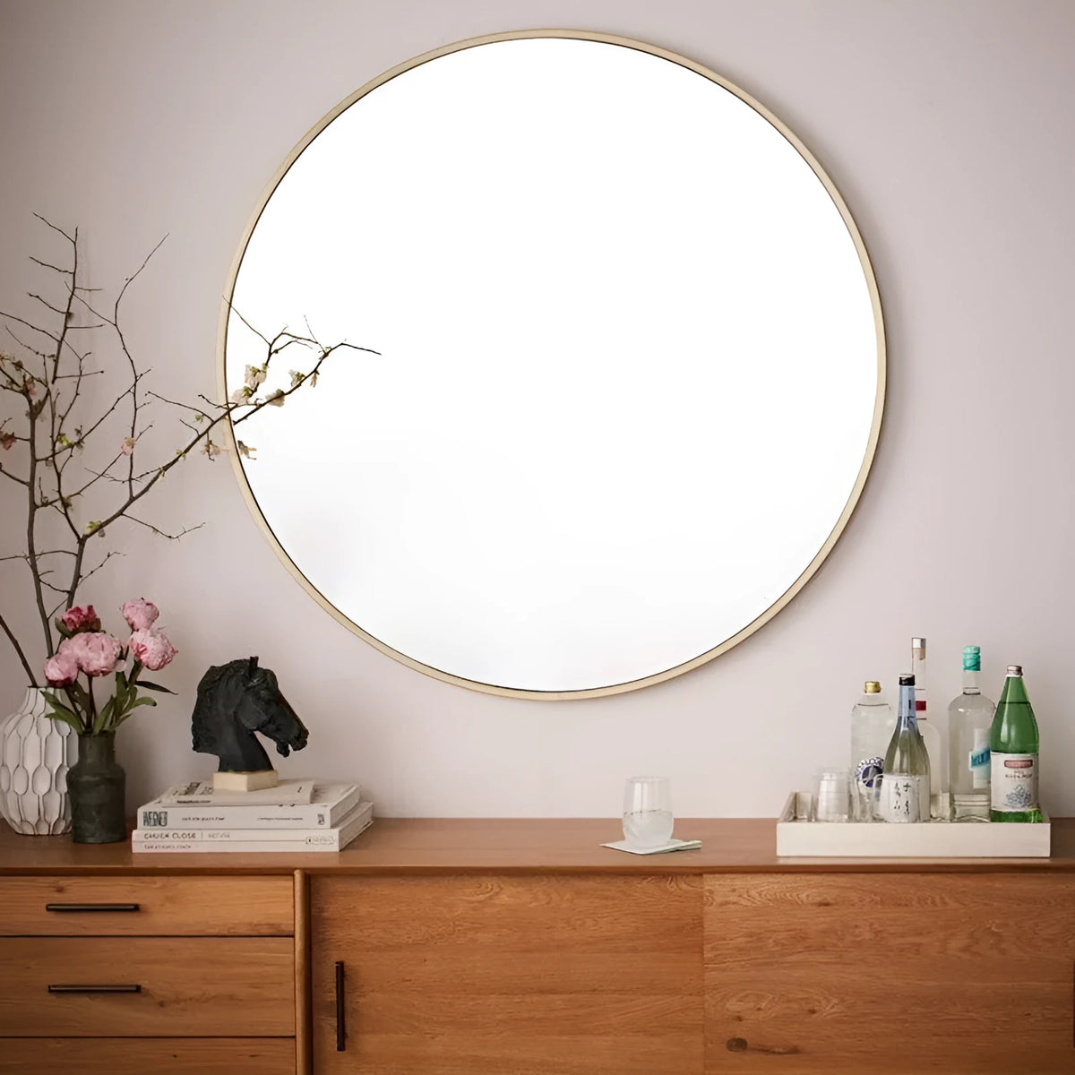 Round metal wall mirror in black finish, shown on a bathroom wall.