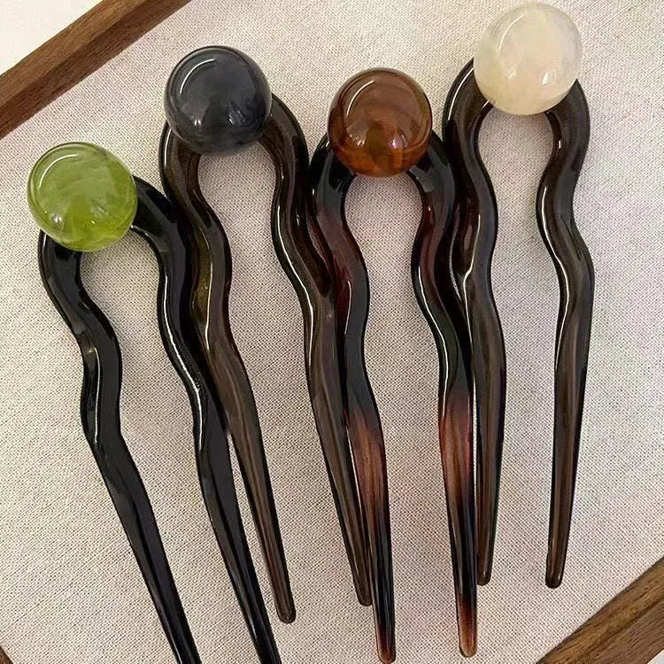 Acrylic U-shaped hair barrette with a small spherical decoration in a beige and caramel two-tone colour combination.