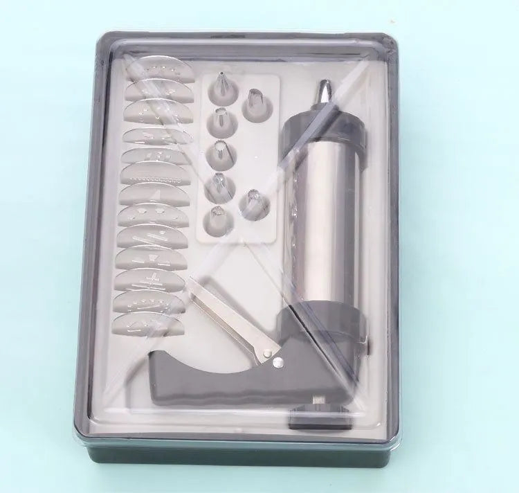 Stainless steel biscuit press gun with assorted cookie moulds and icing nozzles on a baking sheet.