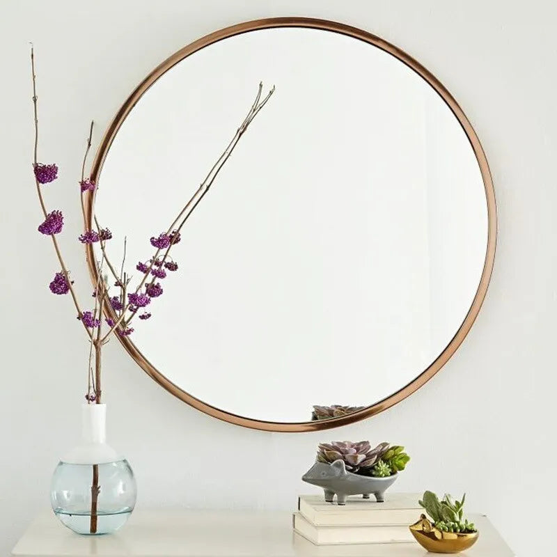 Round metal wall mirror in black finish, shown on a bathroom wall.
