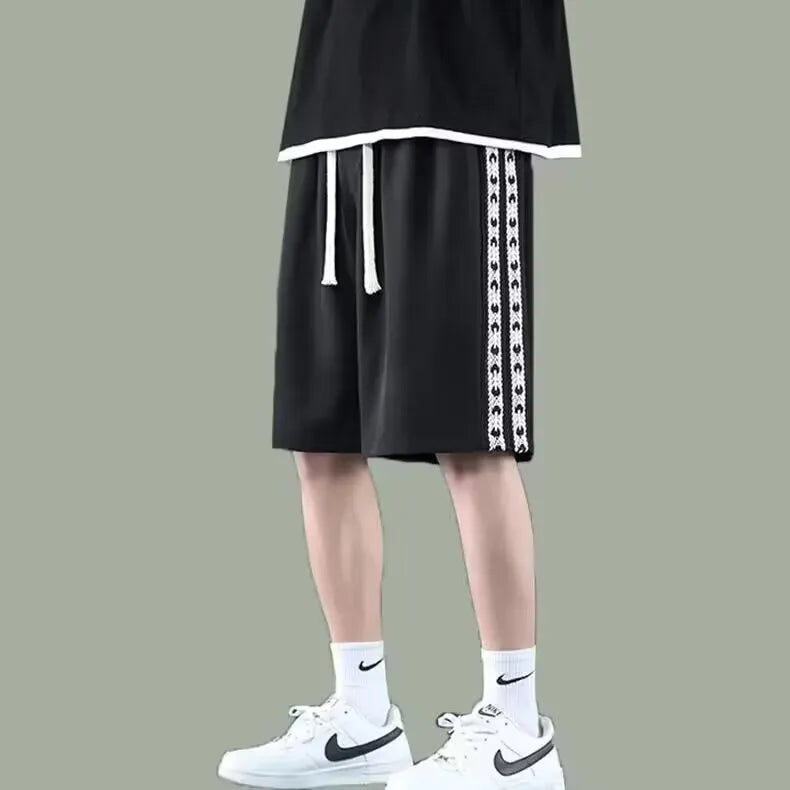 Man wearing loose black track pants with a sporty style, showing the baggy fit and micro elastic fabric.