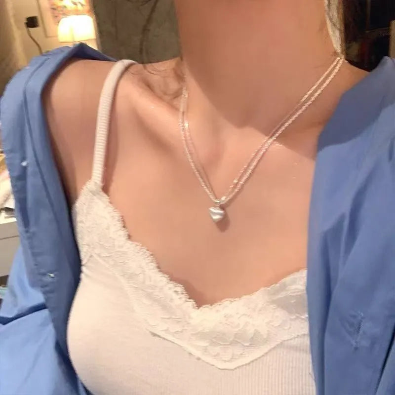 Double-layer brushed heart pendant necklace on model showing adjustable chain length