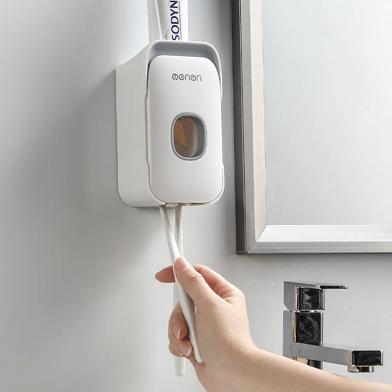 Automatic toothpaste dispenser wall mounted unit in blue, grey or pink colours with no-drip nozzle