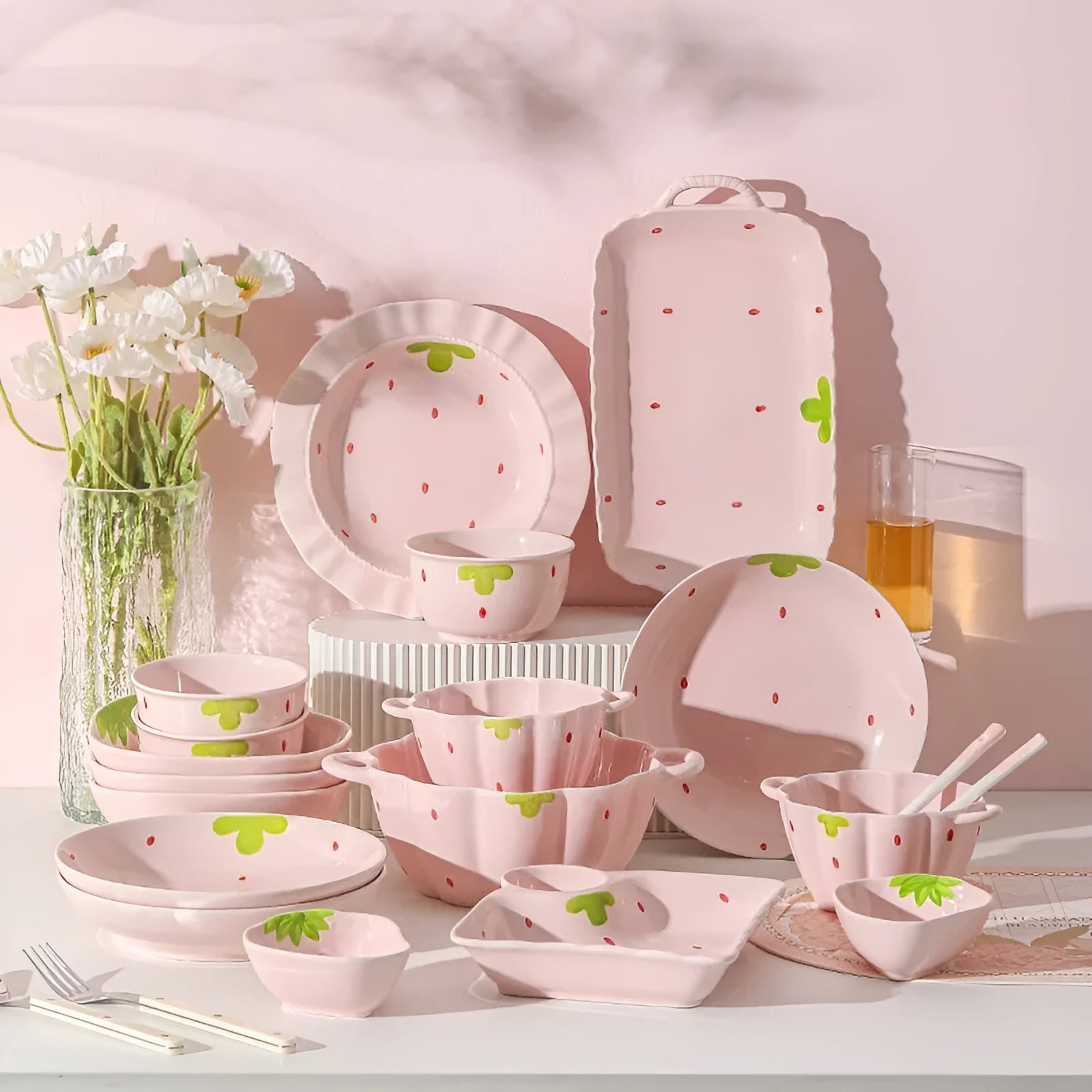 Cute strawberry pattern porcelain dinnerware set with plates, flower bowls, and a twist spoon on a table.