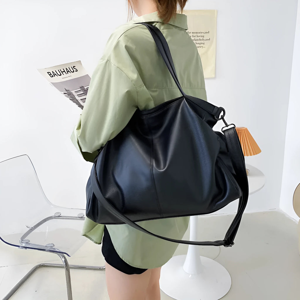 Soft black casual messenger tote bag with zip, showing internal phone pocket and adjustable long shoulder strap.