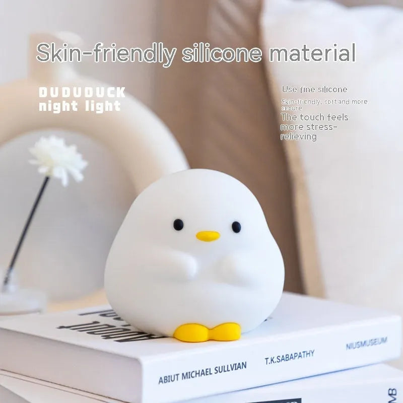 Cute duck shaped LED night lamp with silicone casing and warm light on a bedside table