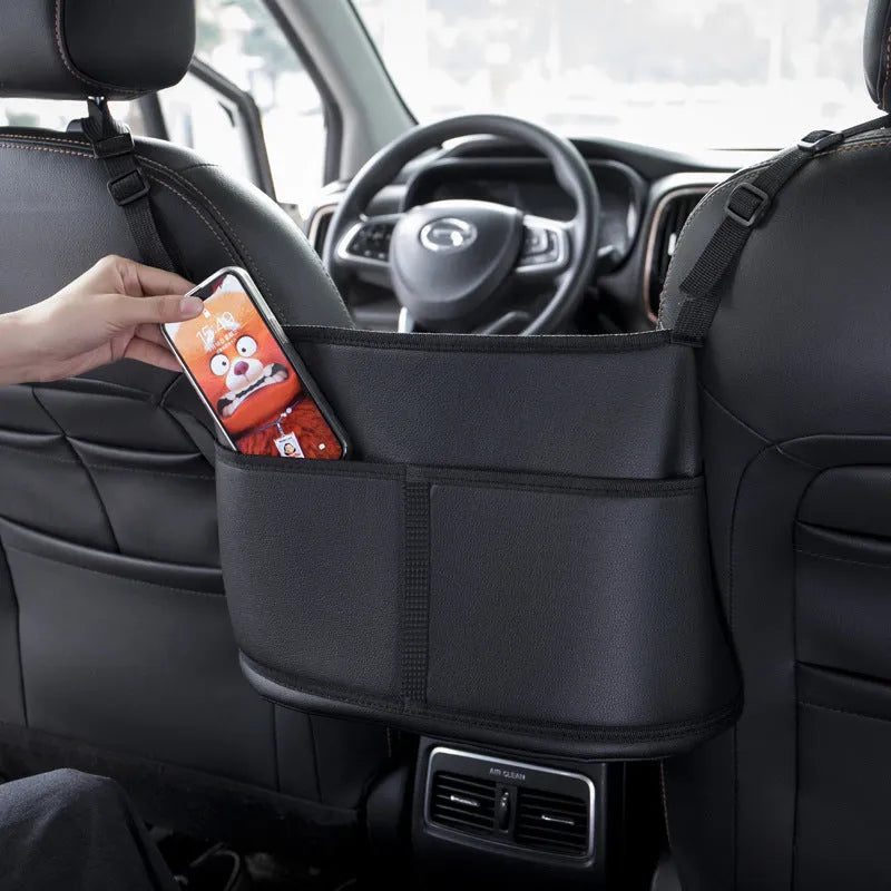 Black leather car seat gap storage organiser bag with carbon fibre pattern, shown between car seats.