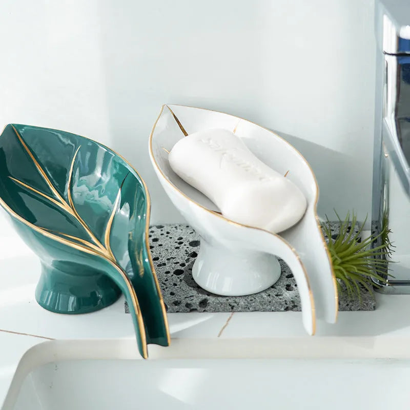 Ceramic leaf shape soap dish with hollow draining base and suction cup, black colour, on bathroom tiles
