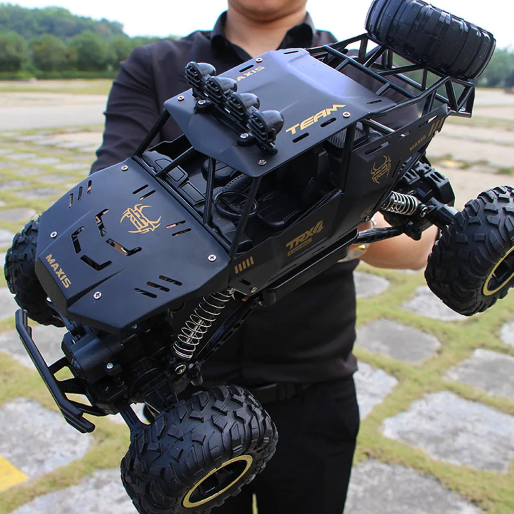 Large black 4WD remote control off-road climbing car on a rocky surface.