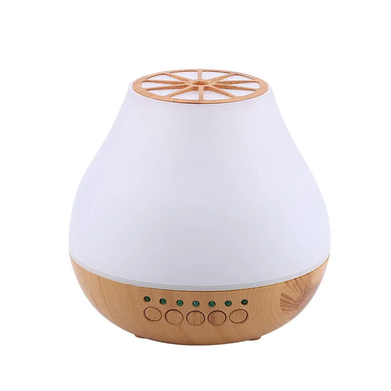Wood grain finish USB aroma diffuser on a table next to a bottle of essential oil.