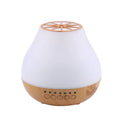 Wood grain finish USB aroma diffuser on a table next to a bottle of essential oil.