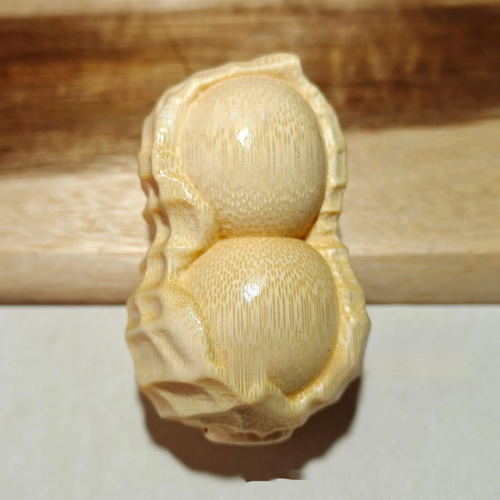 Modern minimalist solid bamboo carving peanut ornament on a neutral background.