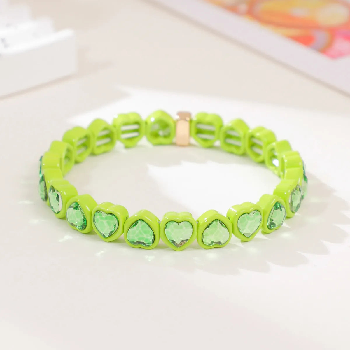 Colourful enamel finish alloy heart charm on a black stretch bracelet band.