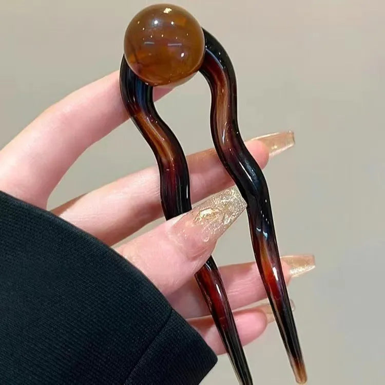 Acrylic U-shaped hair barrette with a small spherical decoration in a beige and caramel two-tone colour combination.