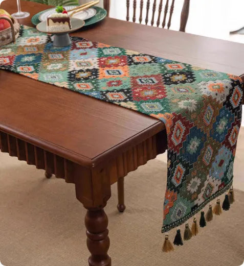 Long blue ginkgo leaf patterned table flag with tassels draped over a wooden sideboard.