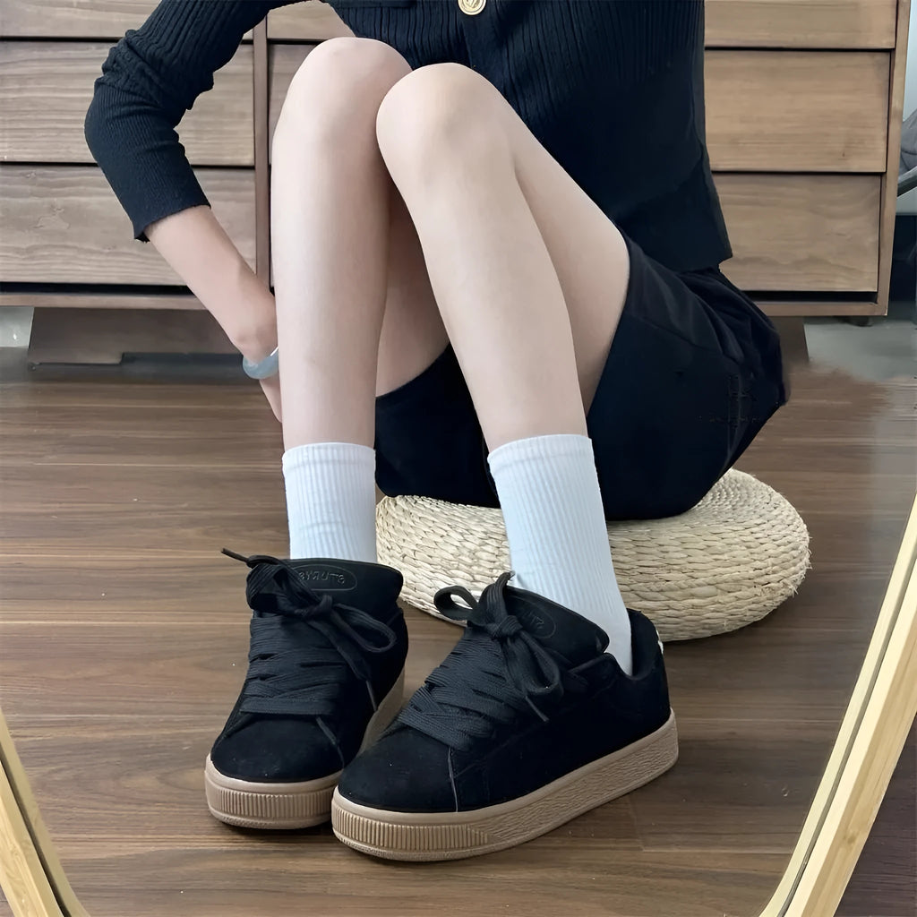 Black retro low-top sneakers with a platform sole and front lace-up closure on a white background.