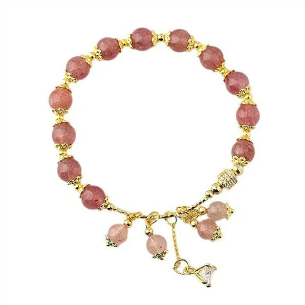 Close-up of a women's pink strawberry quartz crystal bracelet with heart-shaped beads and pearl accents.