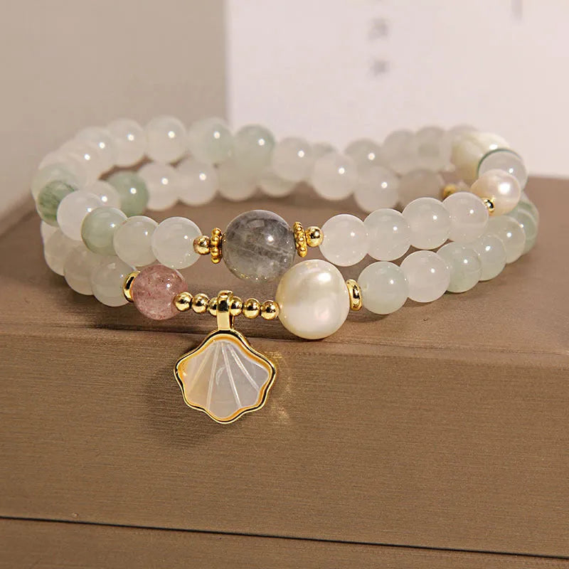 Women's crystal bracelet with gold ginkgo leaf pendant and rhinestones on a white background.