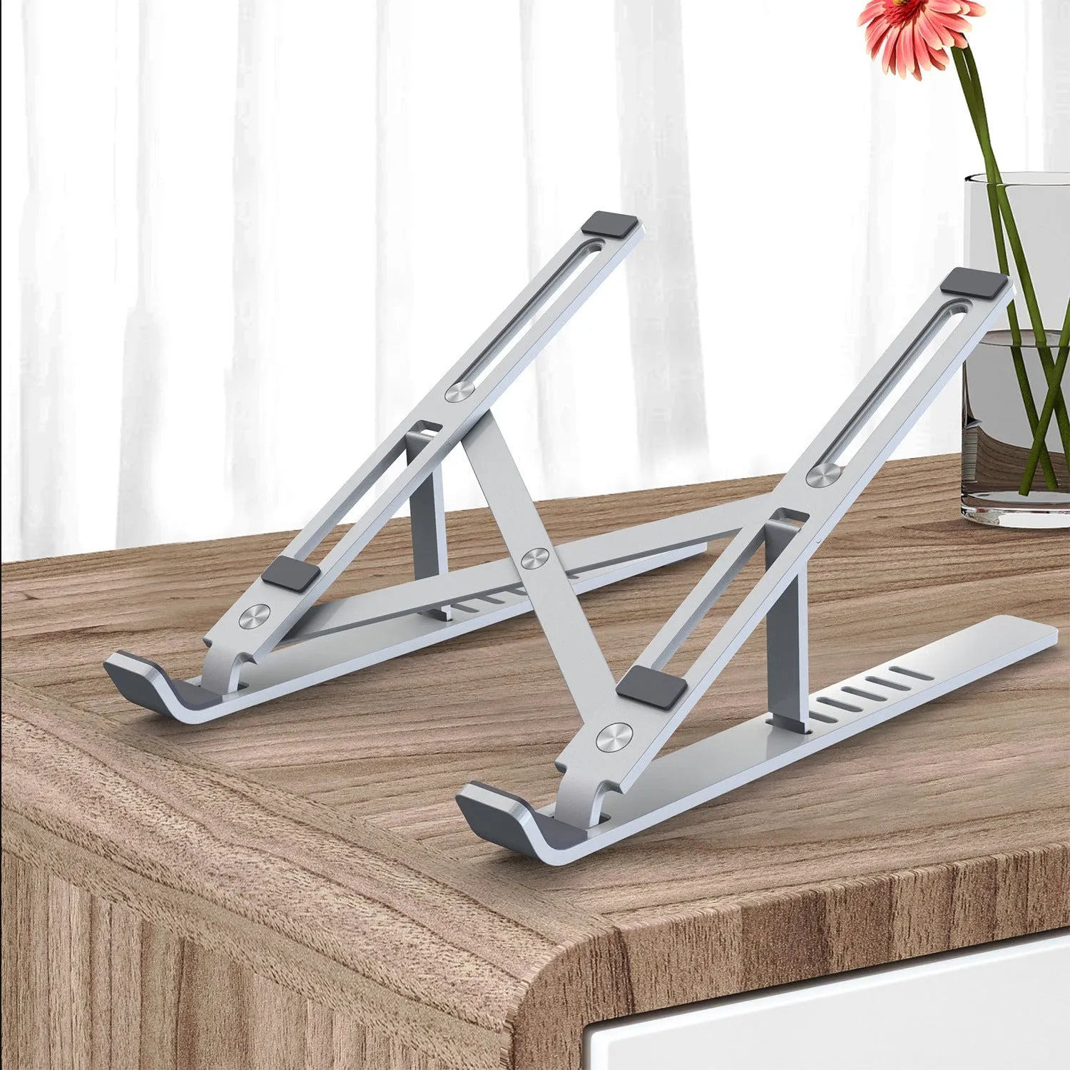 Silver aluminium alloy portable laptop stand with six-gear adjustment folded on a desk