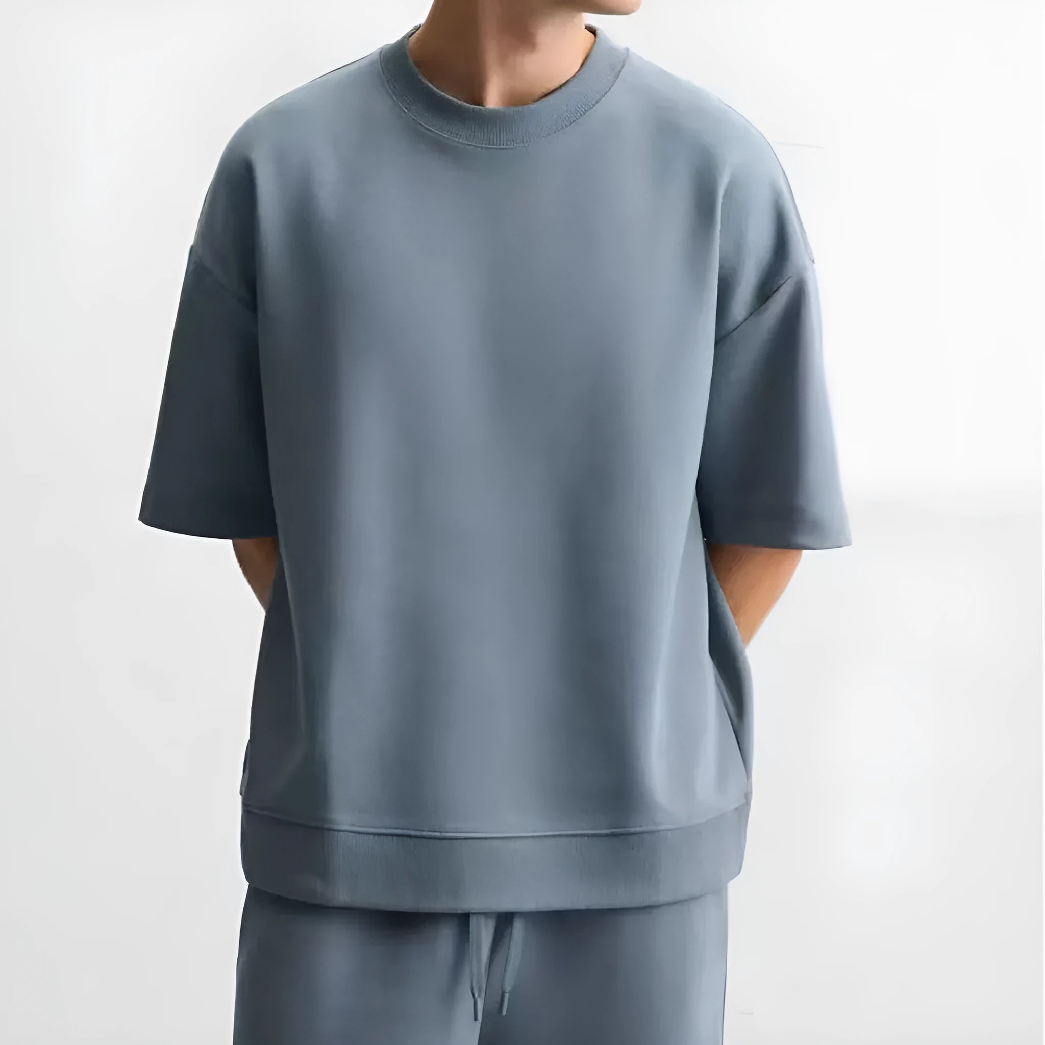 Man wearing a loose blue short sleeve top and matching blue shorts from a casual loungewear set.